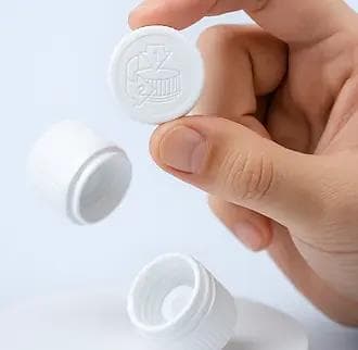 Person holding a white child-resistant, tamper-evident plastic cap, with additional caps displayed on a clean surface against a light blue background.
